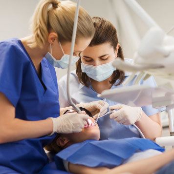 2 dental assistants working together to clean a patients mouth